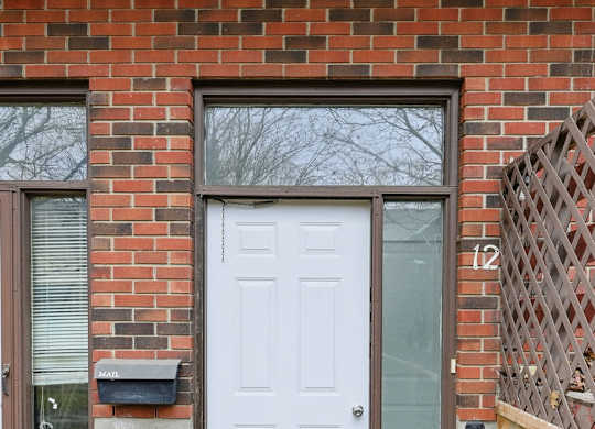 A white door is on the front of a brick house.