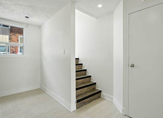 A white room with a staircase leading to the next floor.
