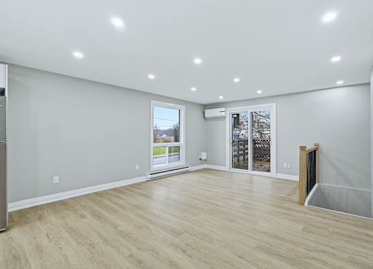 A spacious room with wooden flooring and white walls.