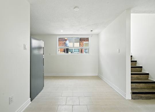 A kitchen with a refrigerator and a window with a view of a city.