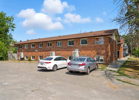 Two cars parked in front of a brick building.