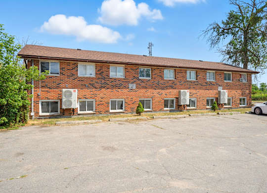 A large red brick building with a parking lot in front.