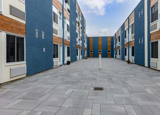 A long, narrow courtyard between two buildings with blue and white walls.