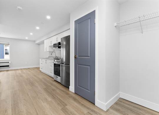 A kitchen with a grey door and white cabinets.