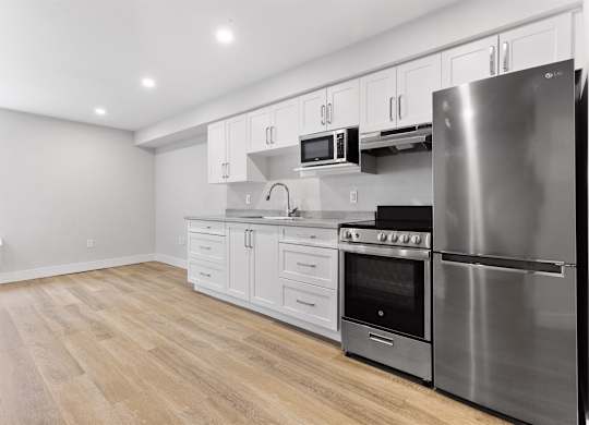 A modern kitchen with stainless steel appliances and wooden flooring.