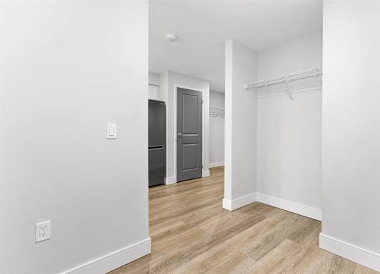 A white room with a wooden floor and a closet with a door.