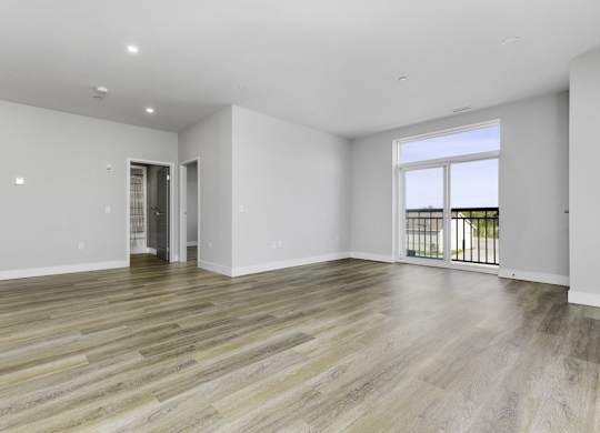 A spacious room with wooden flooring and white walls.