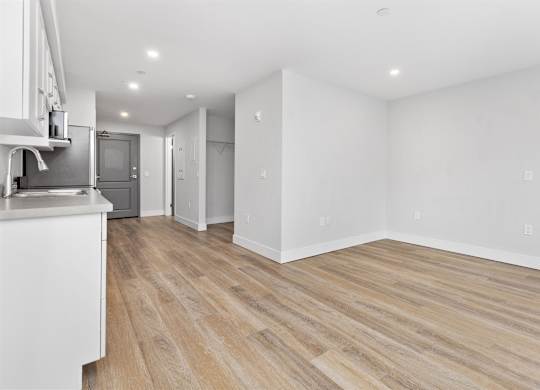 A kitchen with white cabinets and a wooden floor.