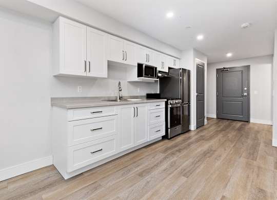 A kitchen with white cabinets and black appliances.