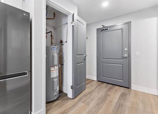 A kitchen with a refrigerator and a door leading to a hallway.
