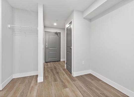 A hallway with a grey door and a white wall.