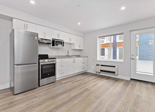 A modern kitchen with stainless steel appliances and wooden flooring.