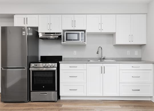 A modern kitchen with a stainless steel refrigerator, oven, and microwave.