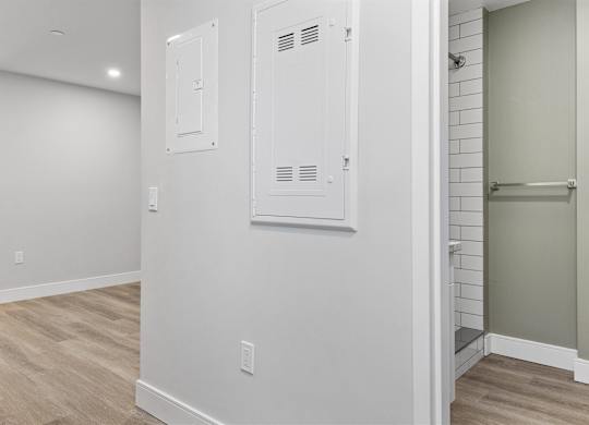 A white bathroom with wood flooring and a white door.
