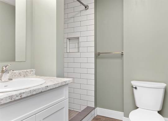 A white toilet sits next to a shower in a bathroom.