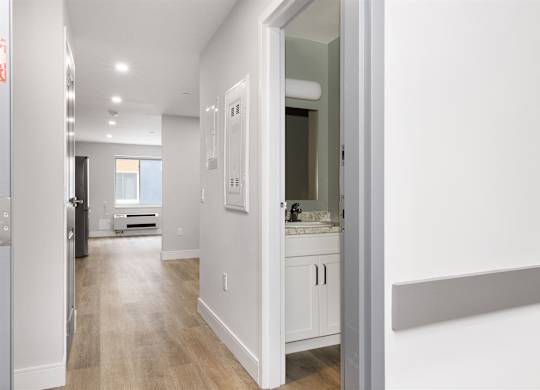 A white kitchen with a refrigerator, sink, and cabinets.