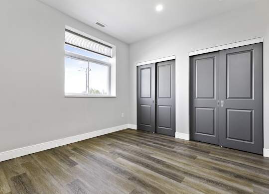 A room with wooden flooring and two grey doors.