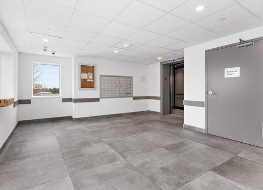A room with a grey floor and a white ceiling with a door on the right.