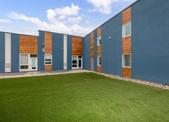A building with a blue exterior and a green lawn in front.