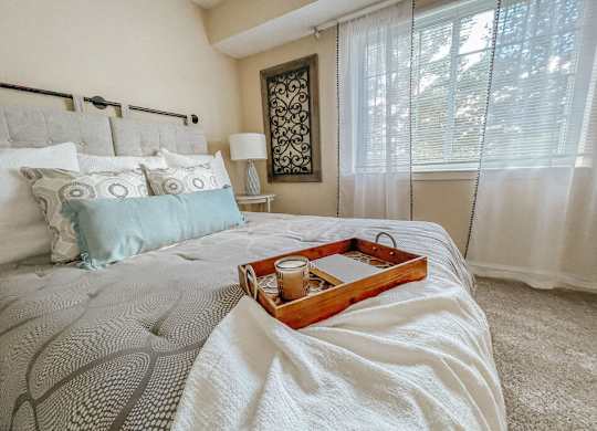 A tray with a candle and a glass sits on a bed.