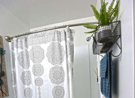 A white toilet in a bathroom with a shower curtain and a plant.