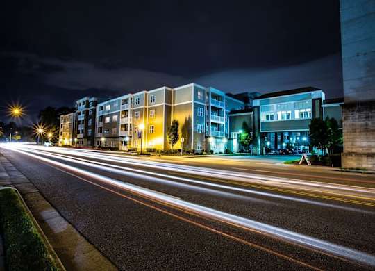 A long exposure shot of a street at night with light trails from moving vehicles.