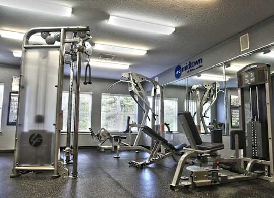 A gym with a variety of equipment including a squat rack, a leg press machine, and a chest press machine.
