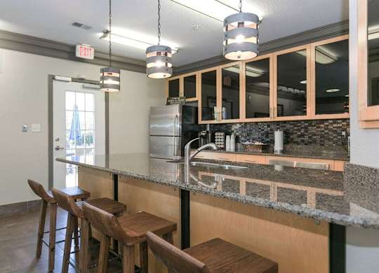 A kitchen with a bar area and wooden stools.
