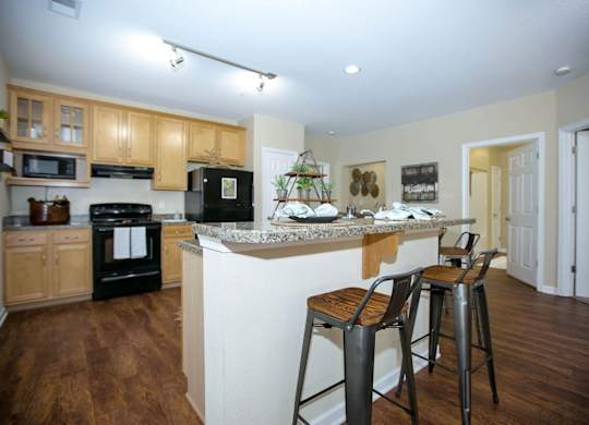 A kitchen with wooden floors and a black refrigerator.