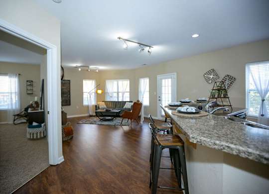 A kitchen with a bar and a living room with a couch and chairs.