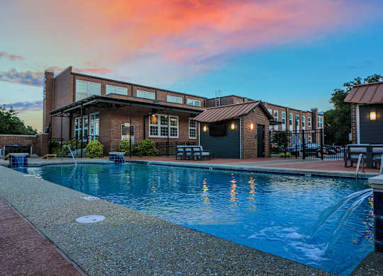 A swimming pool is surrounded by a brick building.