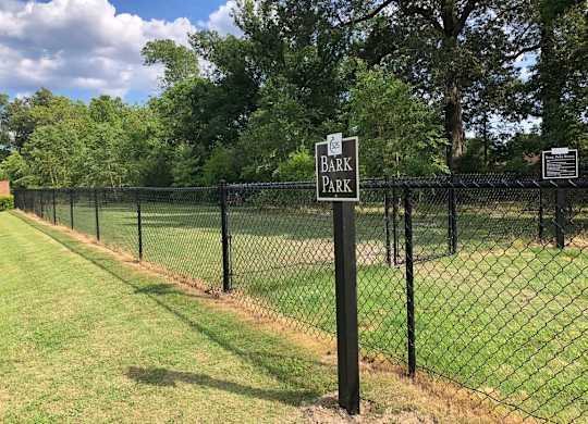 A sign that says Bark Park is on a fence.