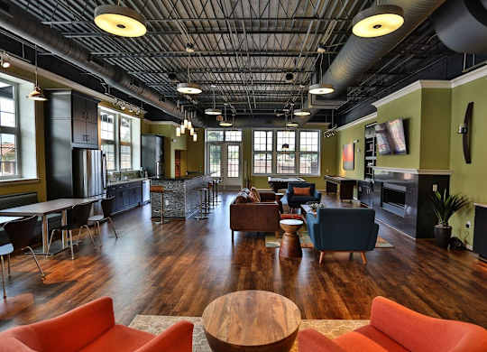 A large room with a wooden floor and a high ceiling with exposed pipes.
