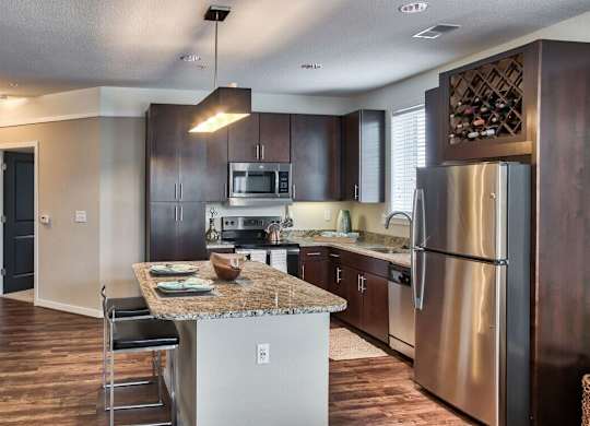 A modern kitchen with dark wood cabinets and stainless steel appliances.