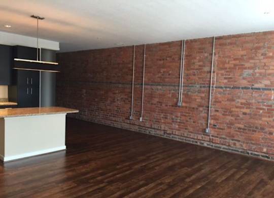 A room with a wooden floor and a brick wall.