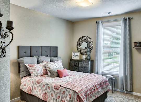 A bedroom with a large bed and a window with curtains.