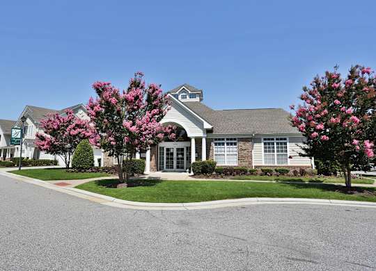 A building with a grey roof and a tree with pink flowers in front.