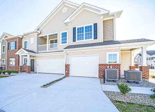 A large, two-story house with a garage and a driveway.