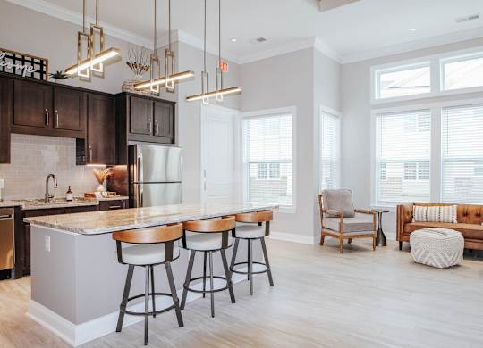 A kitchen with a bar and stools in front of it.