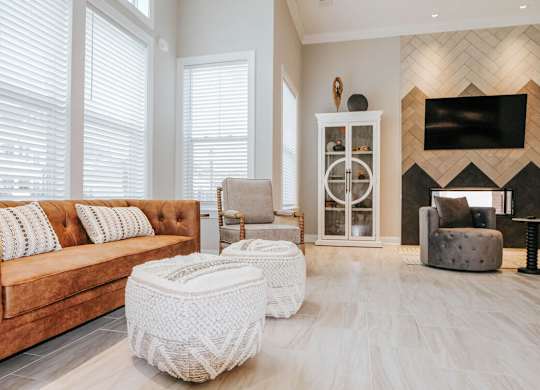 A living room with a brown couch and a white ottoman.