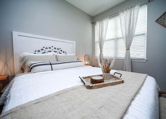 A white bed with a tray of food on top of it.