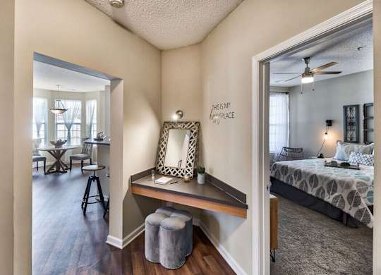 A bedroom with a bed, a desk with a chair, and a mirror on the wall.