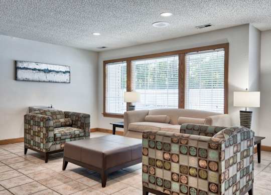 A living room with a couch, chair, ottoman, and lamp.