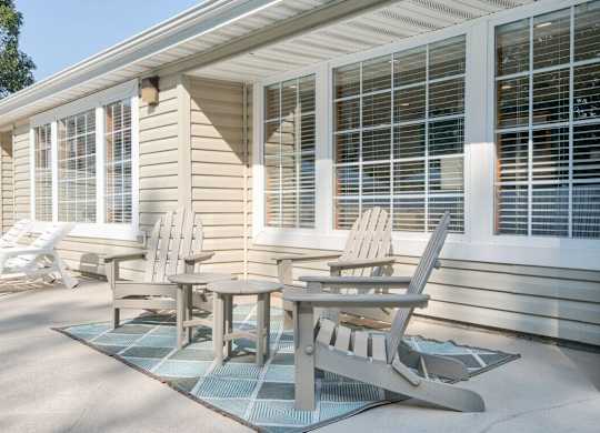 A patio with a table and chairs is in front of a house.