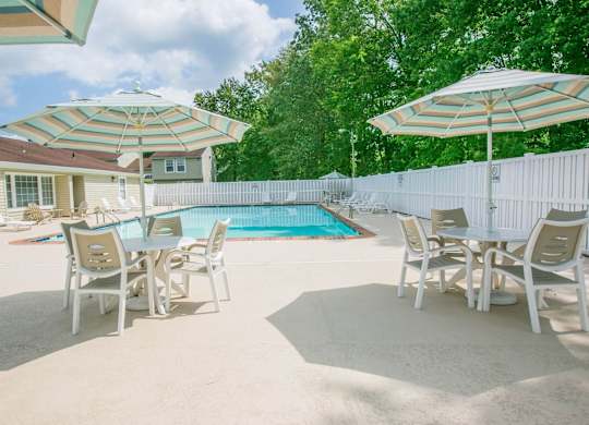 A poolside table set with chairs and umbrellas.
