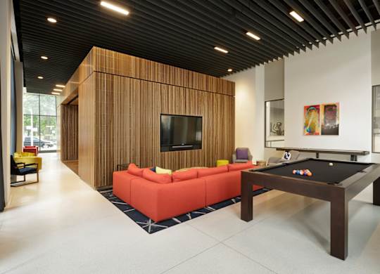 A billiard table is in the middle of a room with a couch and a television.