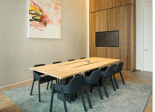 A painting hangs on the wall above a wooden table with chairs.