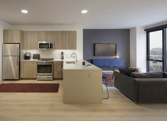 A modern kitchen with a refrigerator, microwave, oven, and sink.