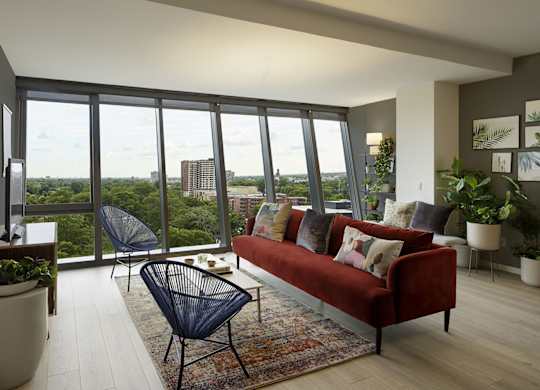 A living room with a red couch and a view of the city.