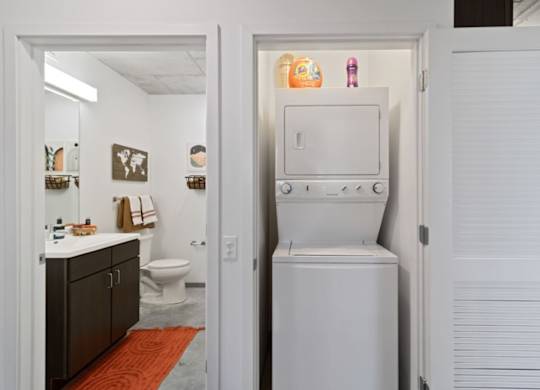 A white refrigerator is in a narrow hallway between two doors.